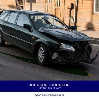 Dark green car with severe front-end damage after a crash.