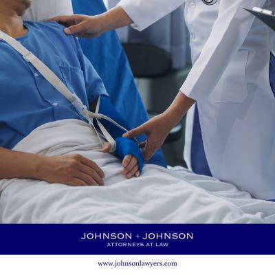 Doctor checking on an injured patient wearing a sling in a hospital bed.