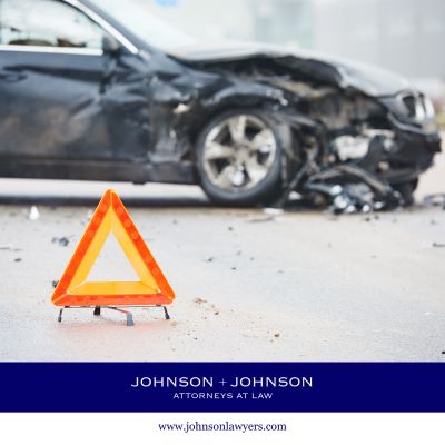 A severely damaged black car in the background after a car accident caused by negligence in Gaston