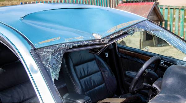 After a car accident, shattered glass from a broken windshield is inside a blue car