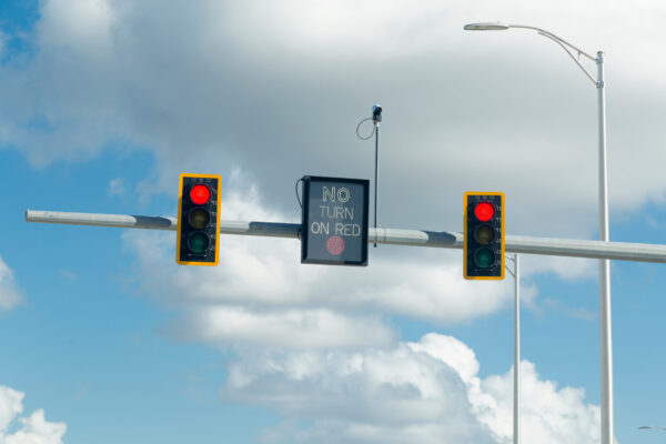 Two red traffic lights on top of a pole with a "NO TURN ON RED" sign in between.