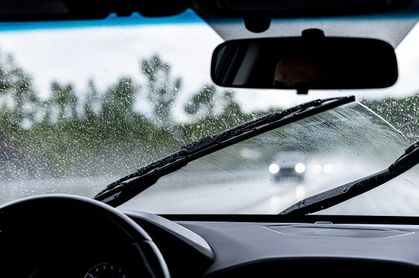 POV of a motorist driving in the rain down a state highway with a vehicle heading toward the driver in the opposite direction.