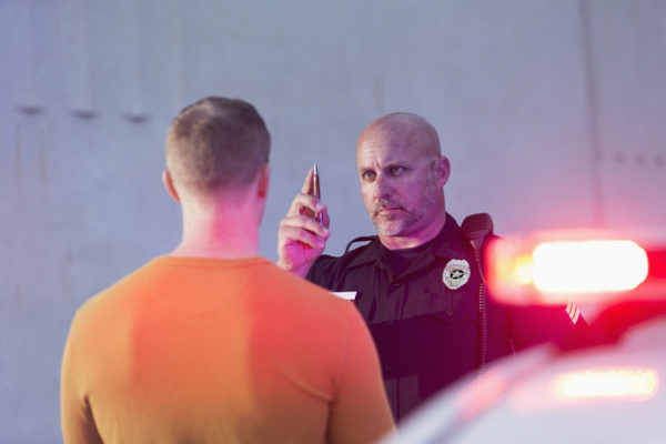 An officer performs a field sobriety test on a male suspected of drunk driving.