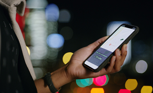 Cropped shot of a person using a smartphone to order food online in the city at night