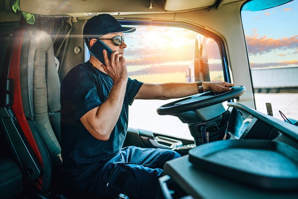 Truck driver talking on a cellphone while driving a semi truck, showing how distracted driving can lead to serious crashes and raise liability issues in commercial truck accident cases.